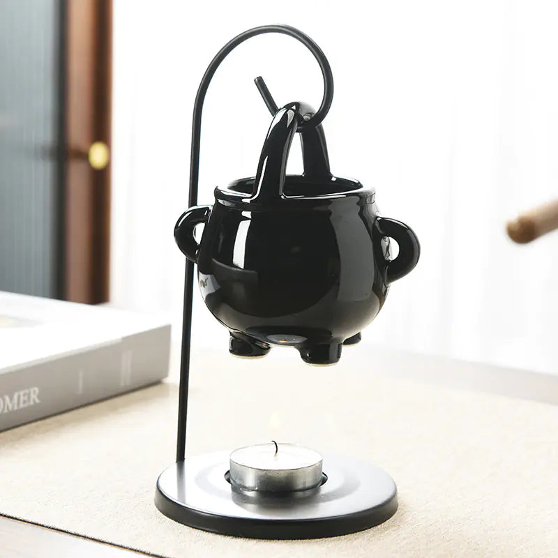 Black ceramic oil burner with a candle on a white surface