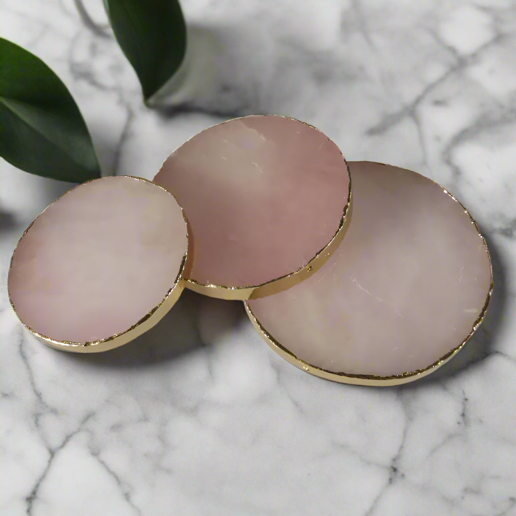 Three pink circular objects with gold edges on a white background