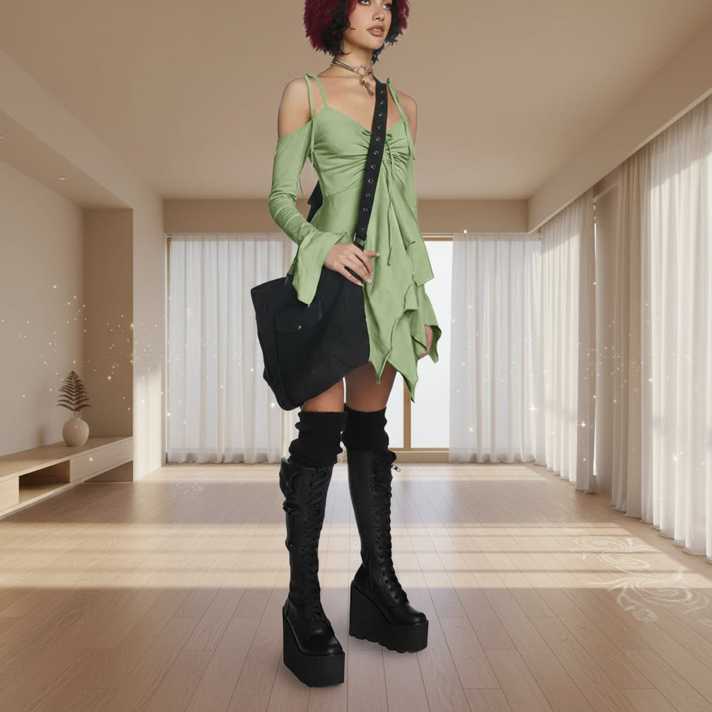 Person wearing a green dress with black accents and black knee-high boots on a white background
