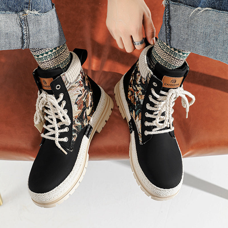 Black lace-up boots with patterned cuffs worn by a person on a white surface.