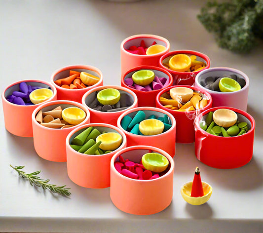 Set of colorful incense cones in different fragrance in small red containers with a white background