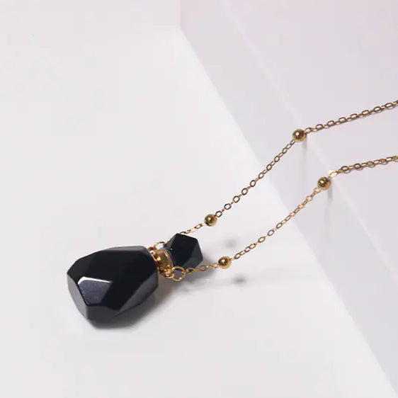 Necklace with black pendant and gold chain on a white background