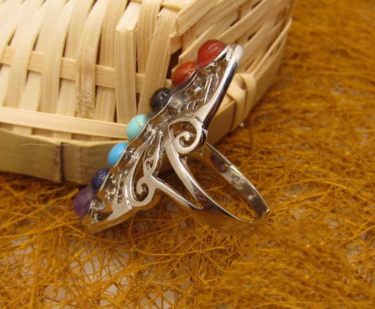 Silver ring with colorful beads on a woven surface