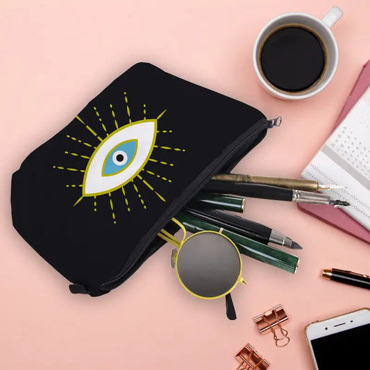 Black pouch with eye design, sunglasses, pens, and phone on a pink surface