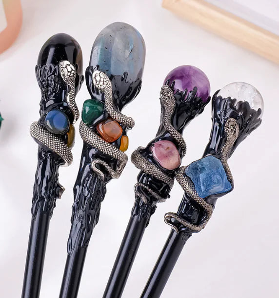 Set of four decorative crystal magic wands with gemstones on a white background
