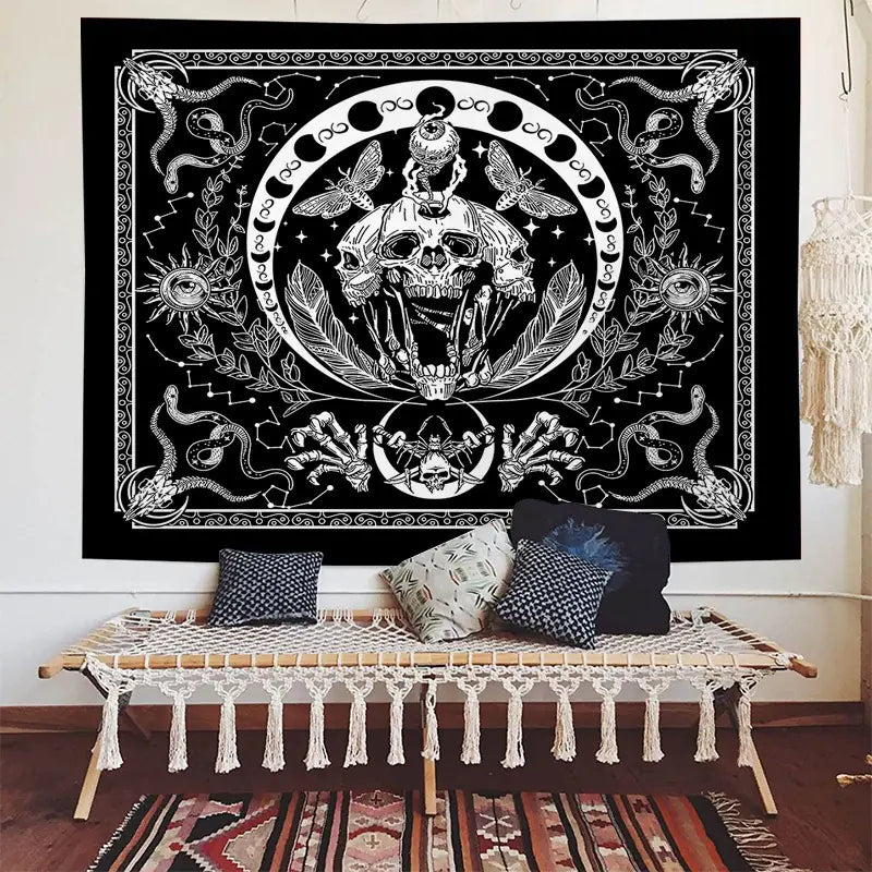 Decorative tapestry with a central skull design in a room with a bench and pillows.