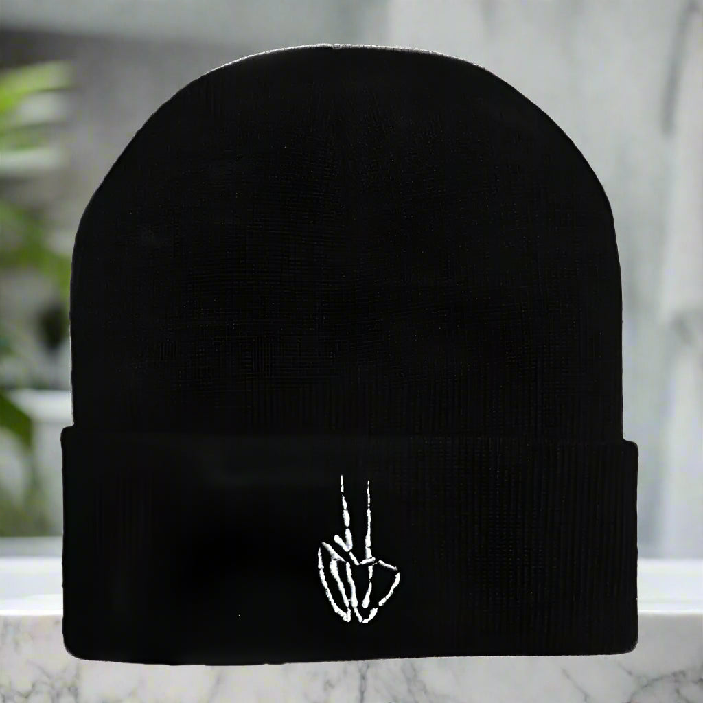 Black beanie with a white embroidered design on a white background