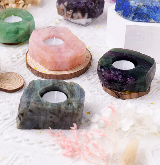 Crystal candle holders in various colors on a textured surface with flowers in the background.