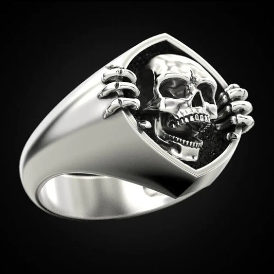 Silver ring with skull design on a black background