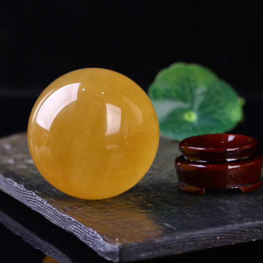 Yellow crystal ball on a dark surface with a blurred green leaf in the background