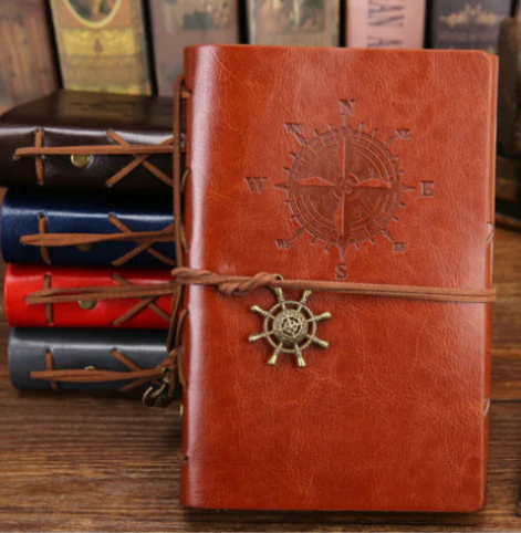Brown leather notebook with compass design on a wooden surface