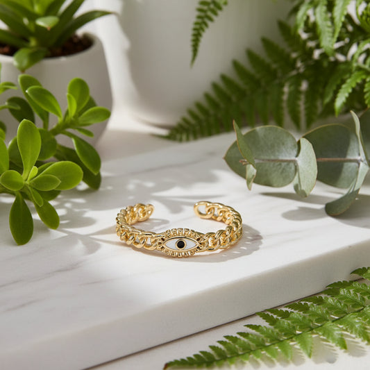 Gold bracelet with eye design on a textured beige surface