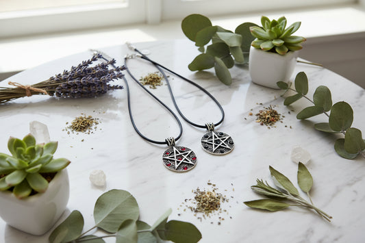 Two pentacle necklaces with red and black stones on black cords against a white background.