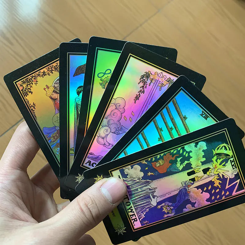 Hand holding colorful tarot cards with intricate designs on a wooden surface
