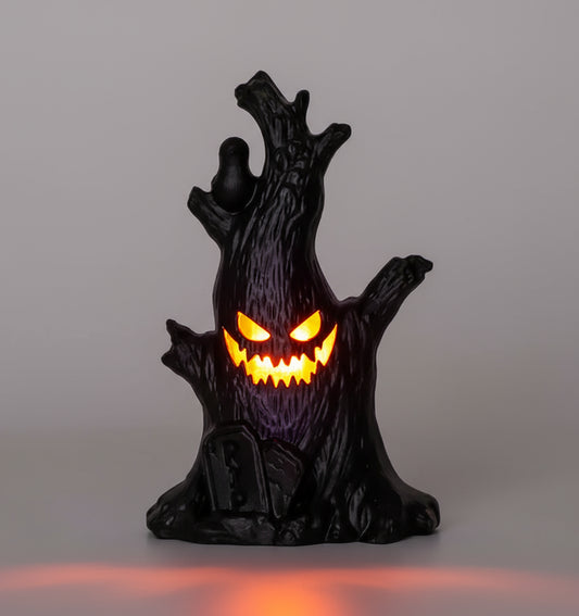 Black tree stump with glowing orange eyes on a blurred Halloween-themed background