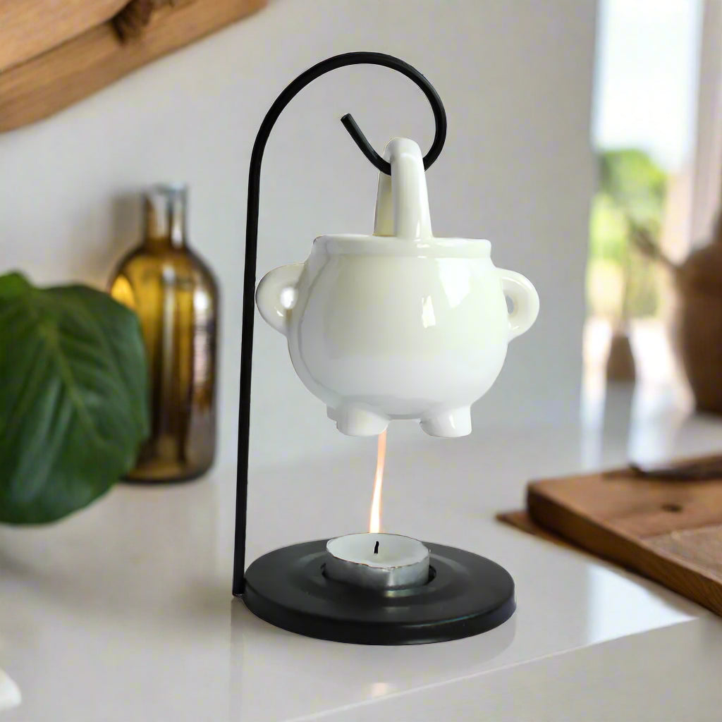 White ceramic oil burner with black metal stand on a white background
