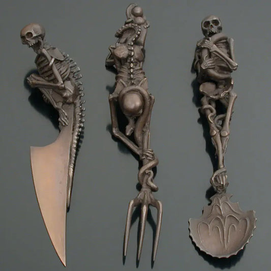 Set of skeleton-themed cutlery including a knife, fork, and spoon on a gray background.