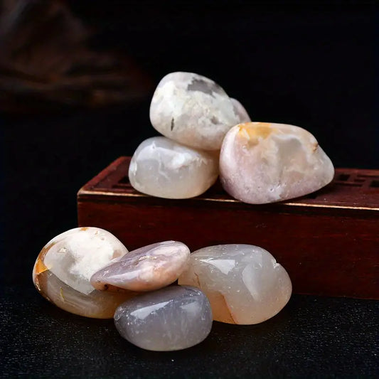 Polished stones on a dark surface with a wooden box in the background