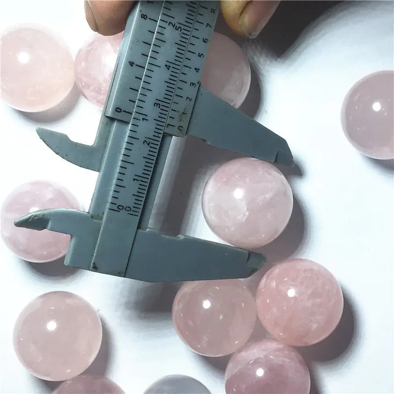 Pink gemstones with a caliper measuring one of them on a white background