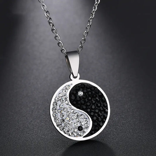 Yin and yang pendant necklace with black and silver design on a dark background
