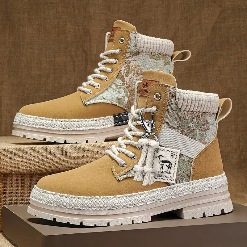 Pair of tan and camouflage boots with white laces on a brown background