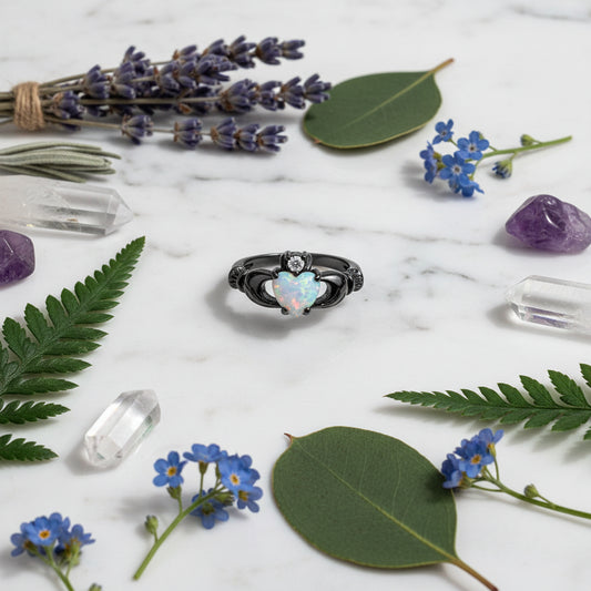 Black-rimmed ring with a heart-shaped opal stone on a white background
