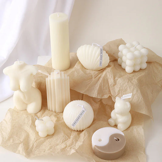 Collection of various white candles and decorative items on a textured surface