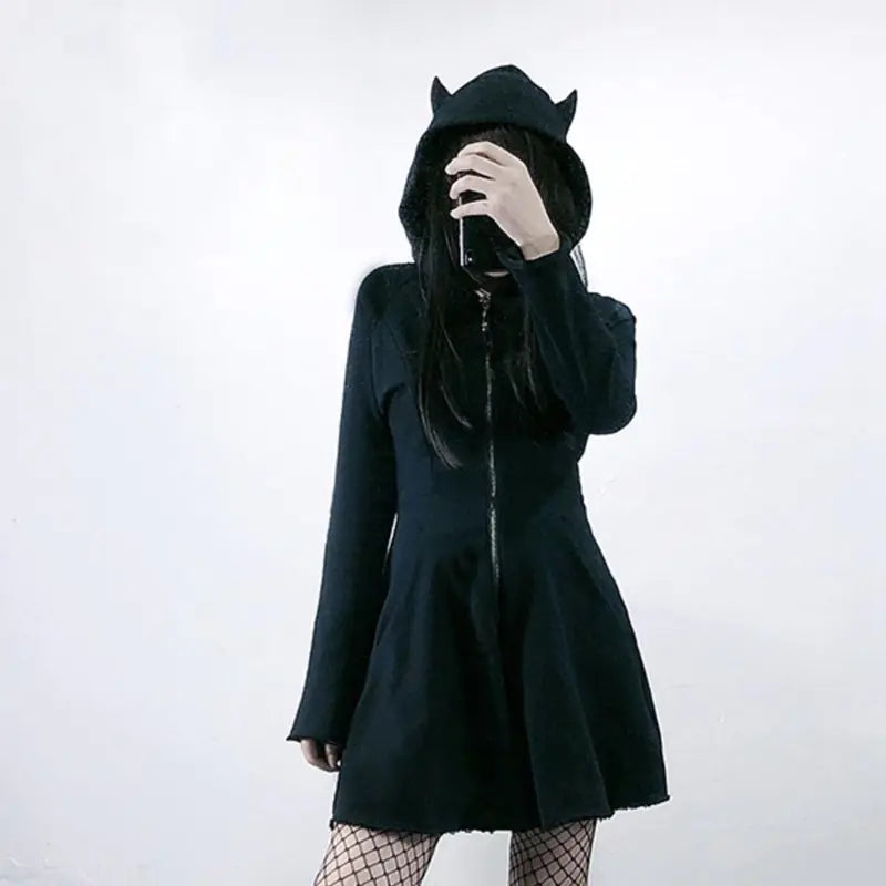 Person wearing a black coat with cat ears on a white background