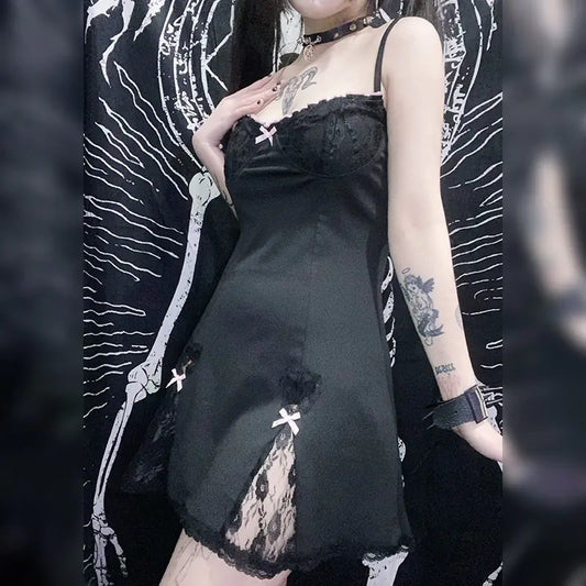 Person wearing a black lace dress with tattoos visible on arms against a dark background