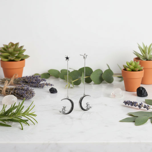 Pair of silver earrings with crescent moon and star designs on a white background