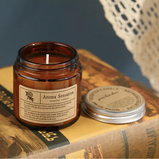 Aroma Sensation candle in an amber jar on vintage books with a lace doily in the background.