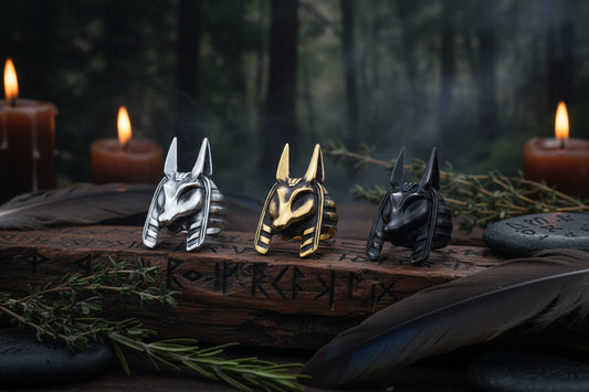 Three metallic anubis Egyptian animal head sculptures on a light blue background