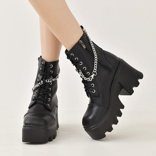 Black platform boots with chain details on a white background