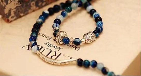Blue beaded bracelet with charms on a textured surface