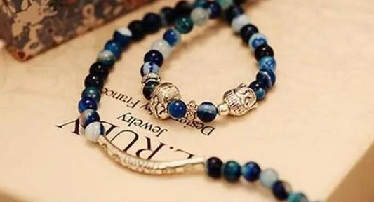 Blue beaded bracelet with charms on a textured surface