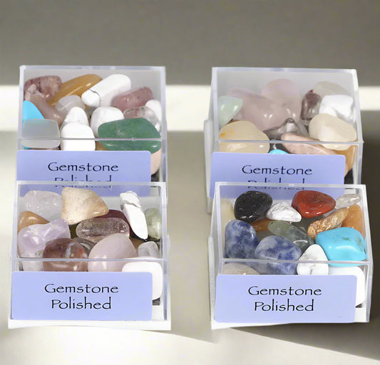 four containers of polished gemstones with labels on a gray background