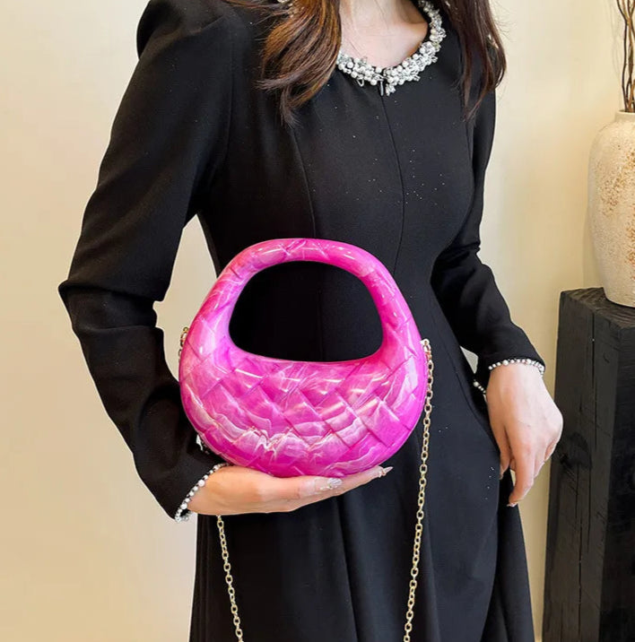 Person holding a pink handbag with a chain strap against a neutral background