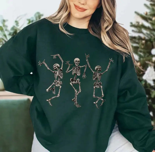 Person wearing a dark green sweatshirt with skeleton designs outdoors.