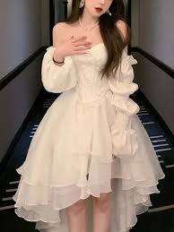 Person wearing a white dress with ruffled sleeves in an indoor setting