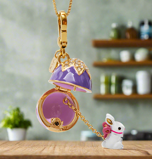 Gold necklace with a purple locket and bunny charm on a white background