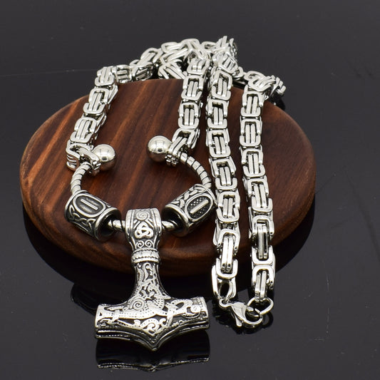 Silver chain necklace with a detailed pendant on a wooden block