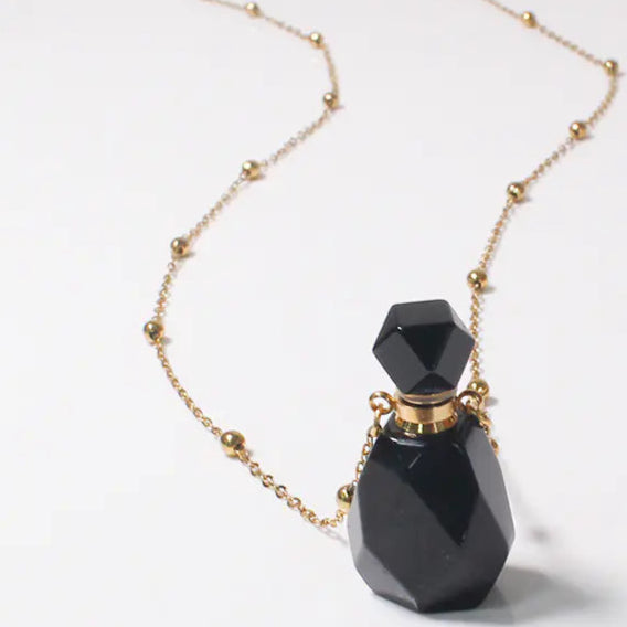 Black perfume bottle with gold chain on a white background