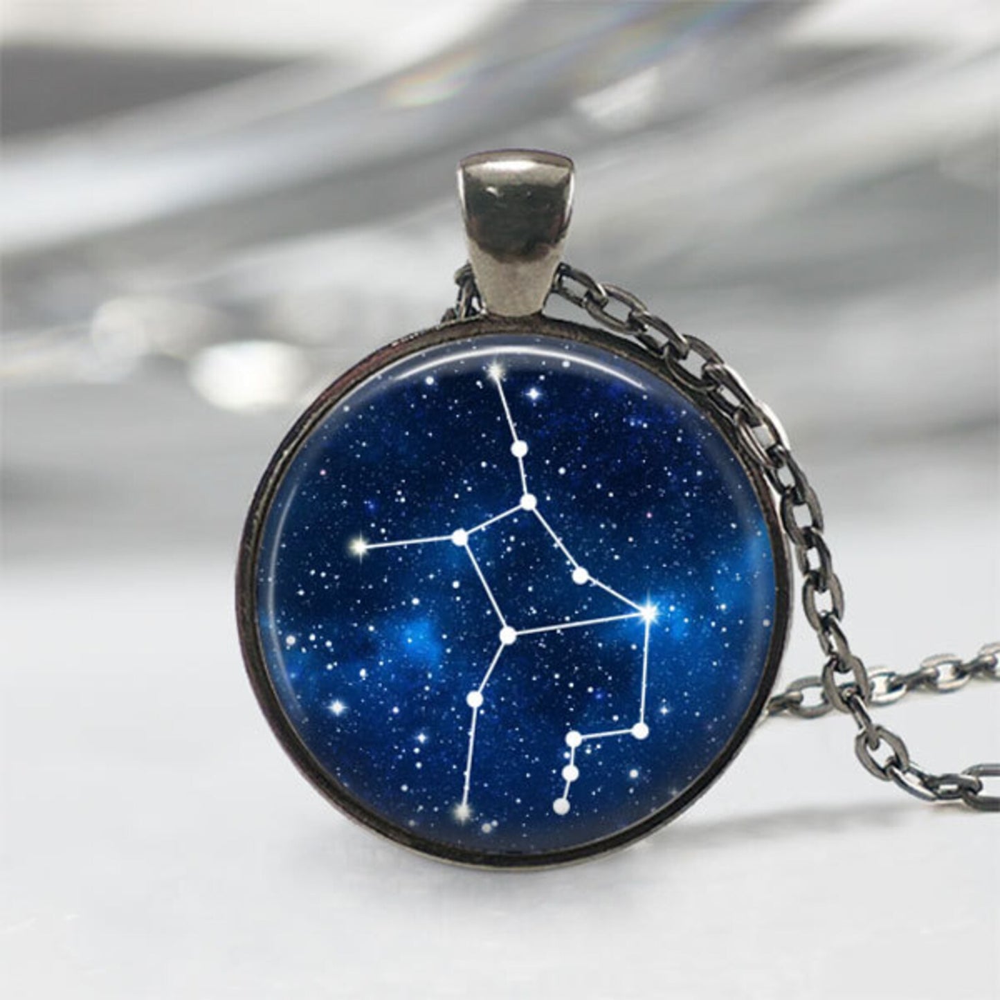 Necklace with a pendant featuring a star constellation design on a blue background.