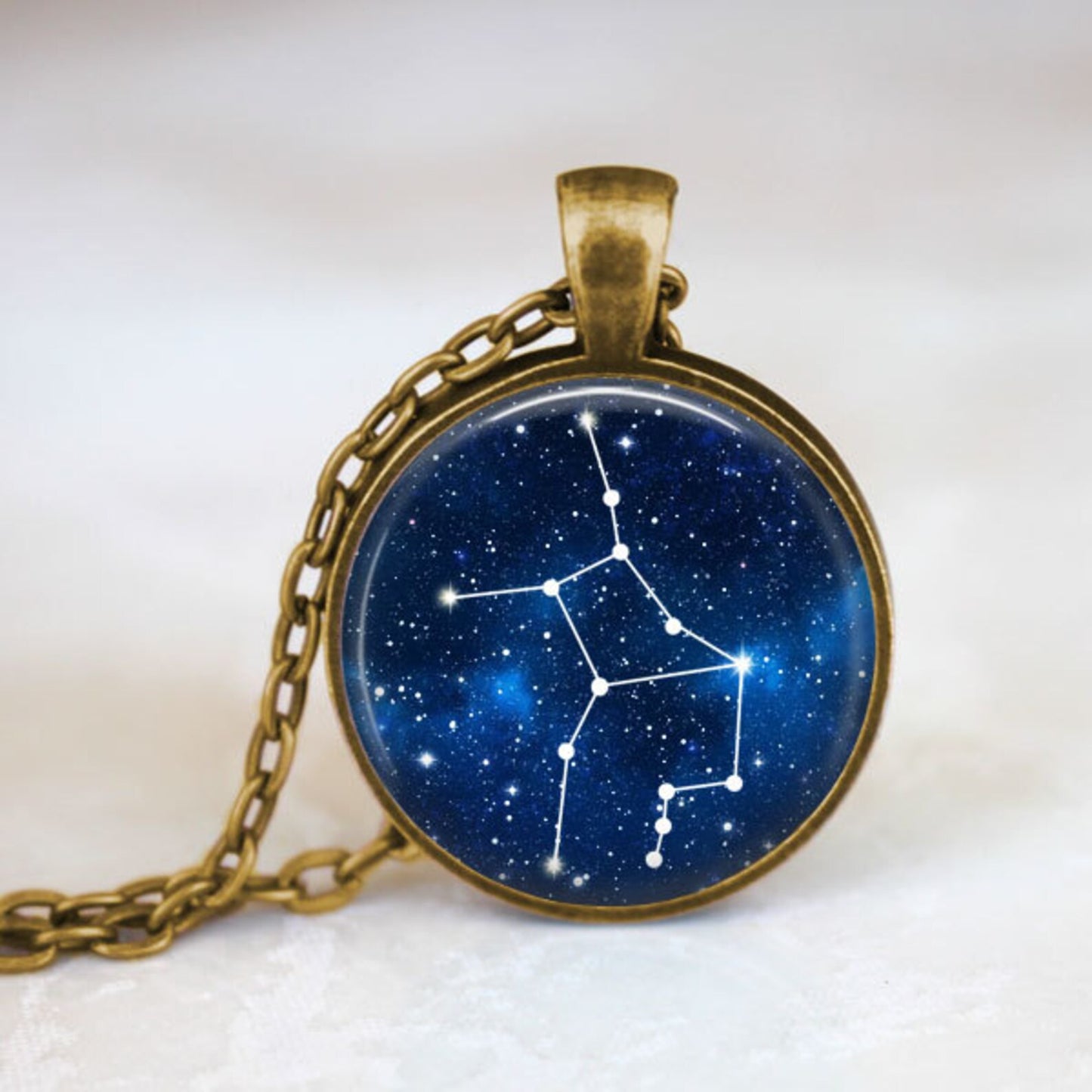 Necklace with a pendant featuring a star constellation design on a blue background.