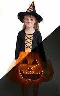 Child in Halloween costume with glowing pumpkin at night
