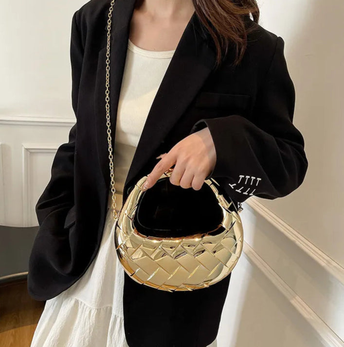 Person holding a gold handbag with a plain background