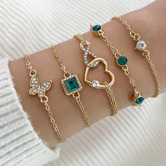 Gold bracelets with gemstones on a wrist against a white background