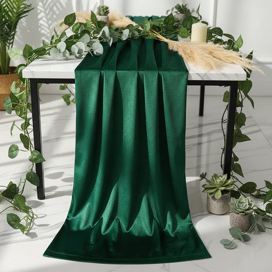 Dining table with a green runner and white tablecloth, set for a meal.