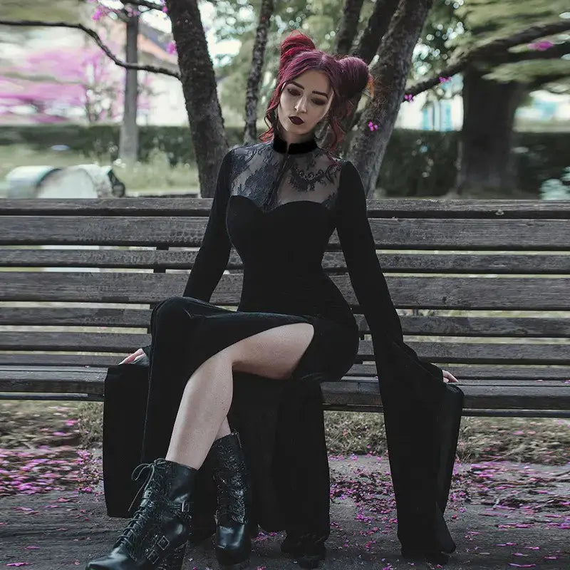 witch in a black dress sitting on a bench with a blurred background