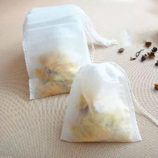 Two white tea bags with yellow contents on a textured beige surface.